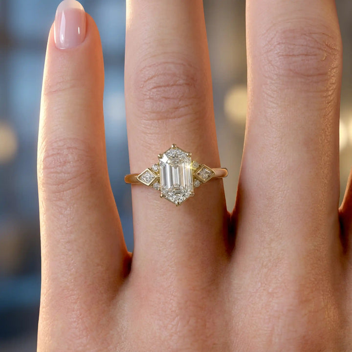 Elongated hexagonal lab-grown diamond engagement ring with side stones on a polished surface.
