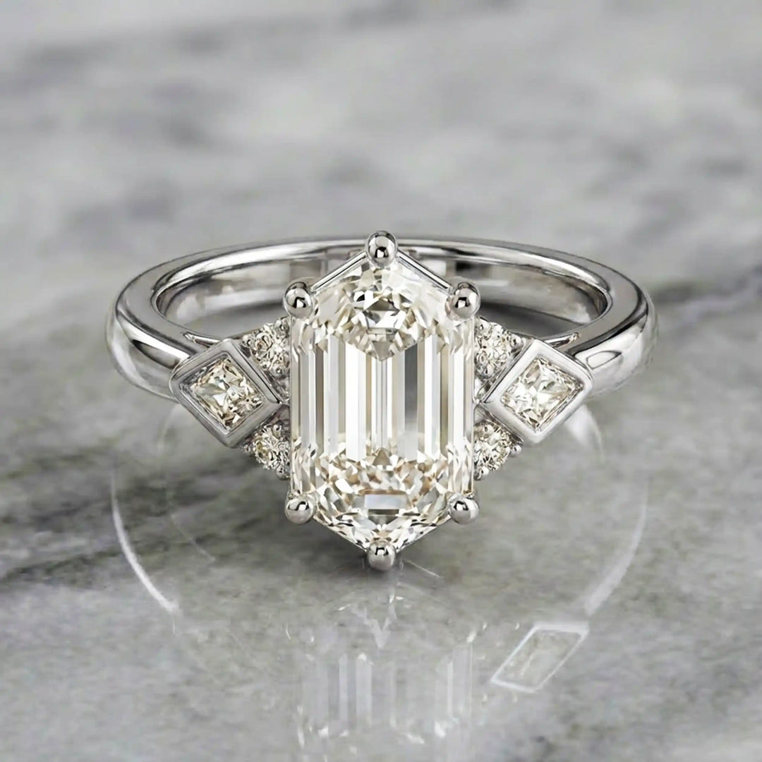 Elongated hexagonal lab-grown diamond engagement ring with side stones on a polished surface.
