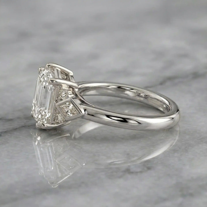 Elongated hexagonal lab-grown diamond engagement ring with side stones on a polished surface.
