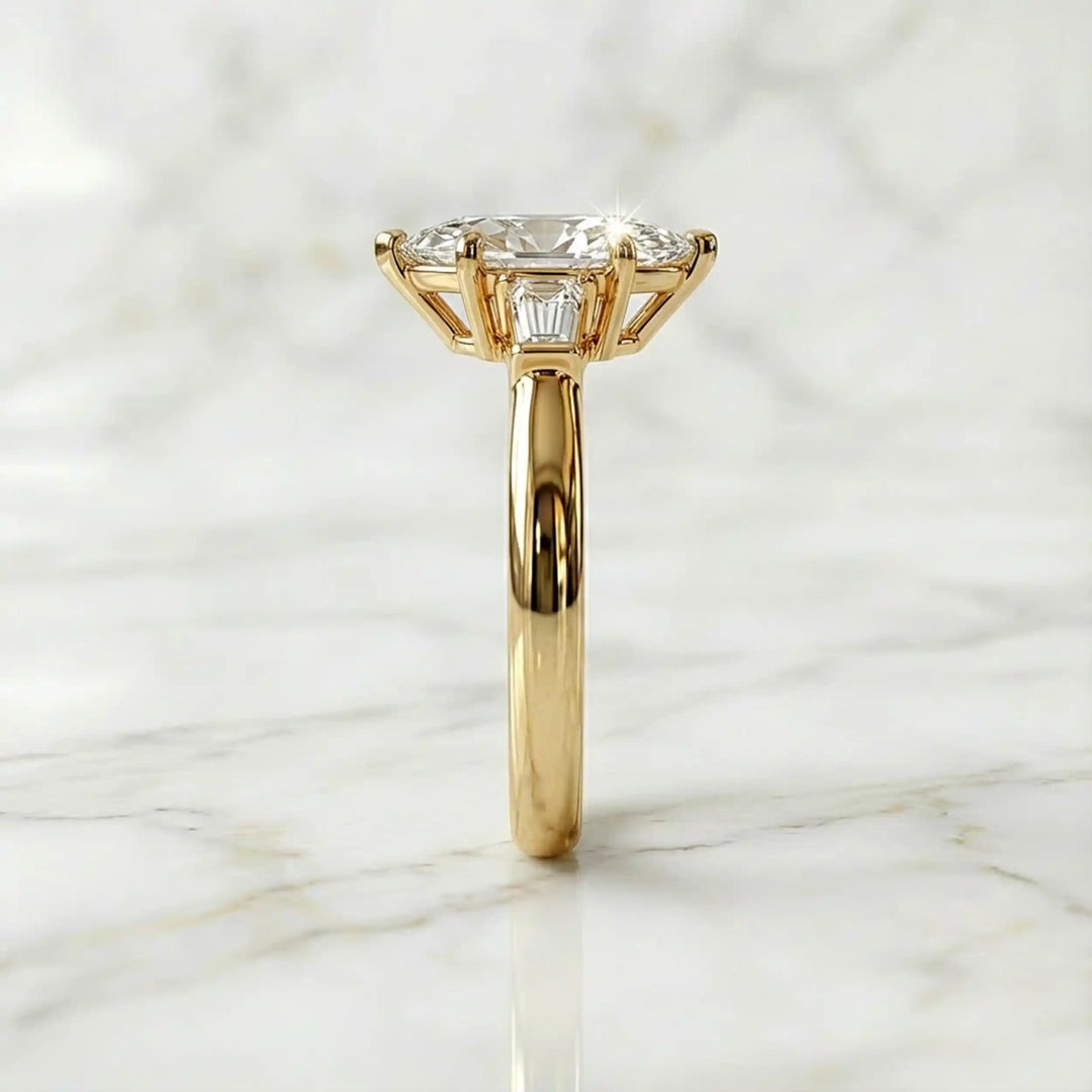 Three-stone marquise lab-grown diamond engagement ring displayed on marble surface.
