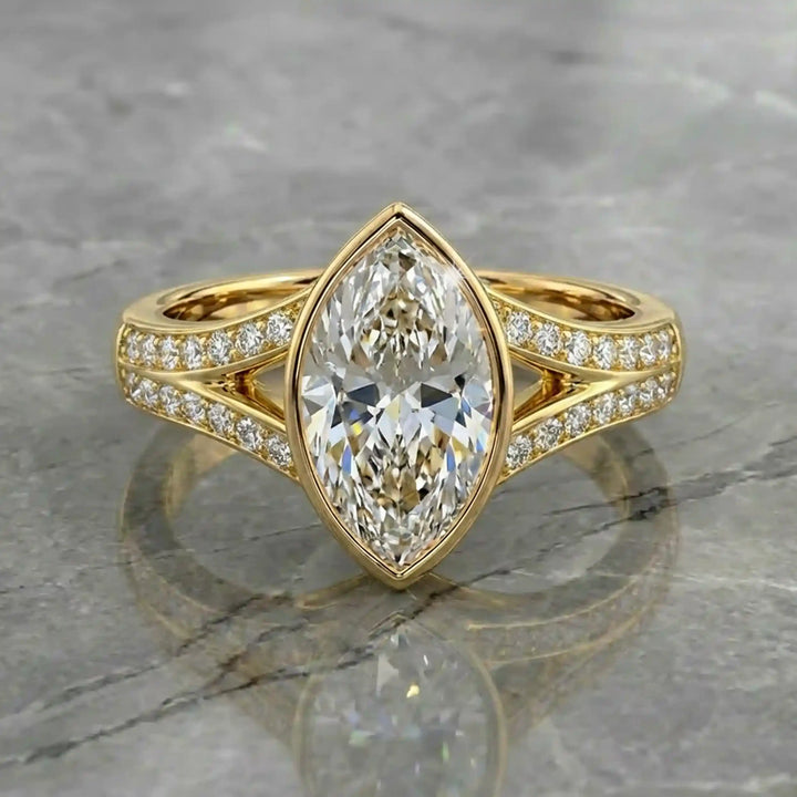 Marquise lab-grown diamond bezel engagement ring with split shank displayed on reflective surface.
