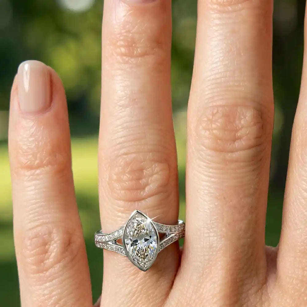 Marquise lab-grown diamond bezel engagement ring with split shank displayed on hand.
