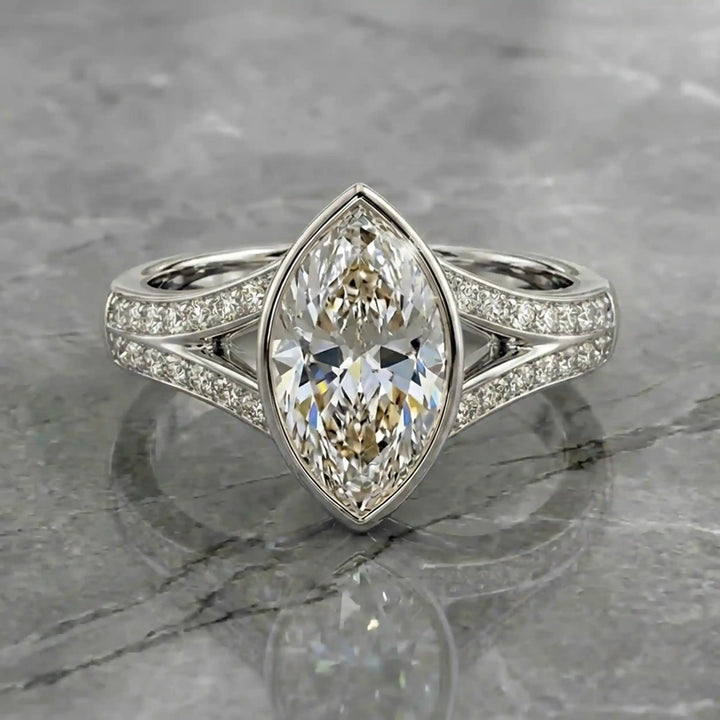 Marquise lab-grown diamond bezel engagement ring with split shank displayed on reflective surface.
