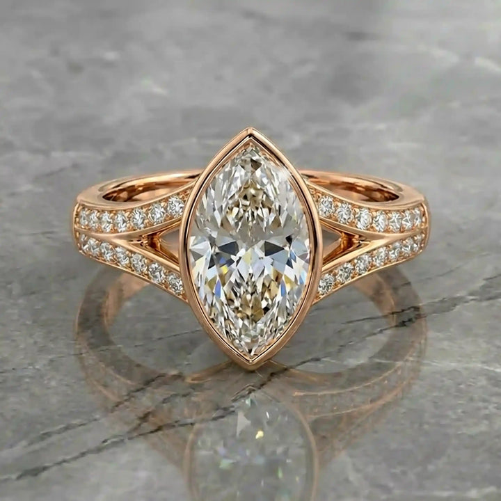 Marquise lab-grown diamond bezel engagement ring with split shank displayed on reflective surface.
