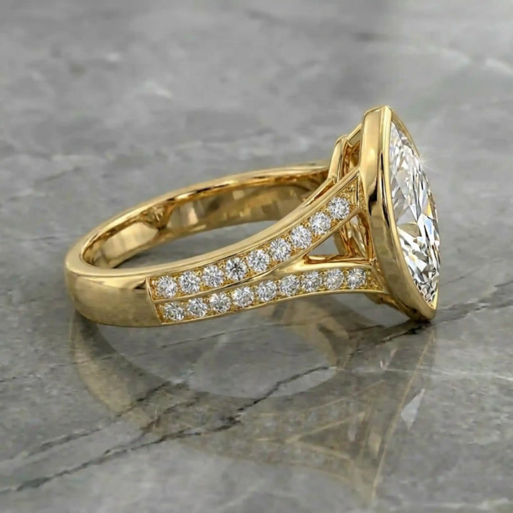 Marquise lab-grown diamond bezel engagement ring with split shank displayed on reflective surface.
