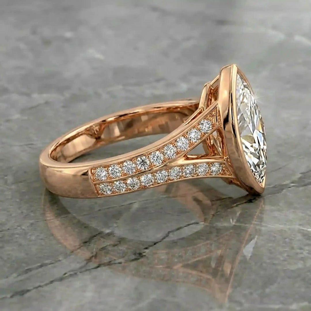 Marquise lab-grown diamond bezel engagement ring with split shank displayed on reflective surface.
