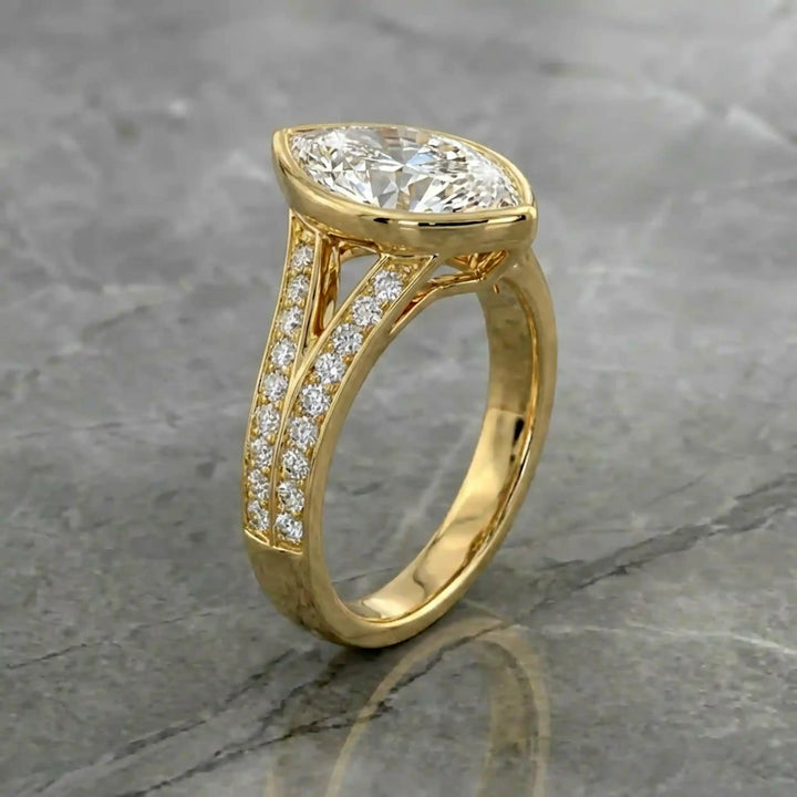 Marquise lab-grown diamond bezel engagement ring with split shank displayed on reflective surface.
