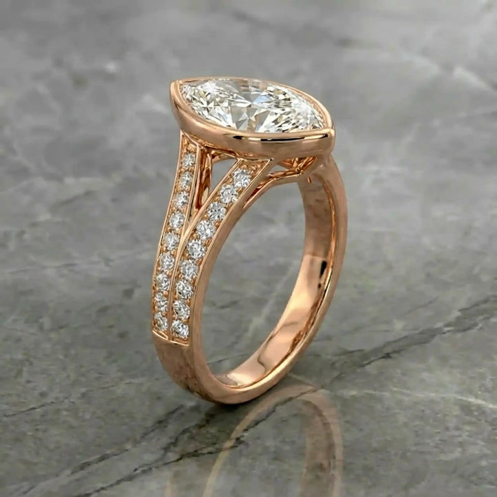 Marquise lab-grown diamond bezel engagement ring with split shank displayed on reflective surface.
