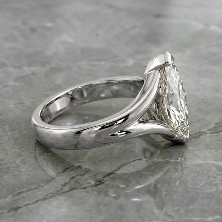 2 carat lab-grown marquise diamond split shank solitaire engagement ring displayed on stone surface.