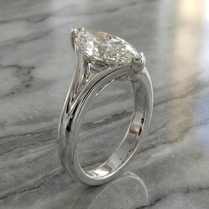 2 carat lab-grown marquise diamond split shank solitaire engagement ring displayed on stone surface.