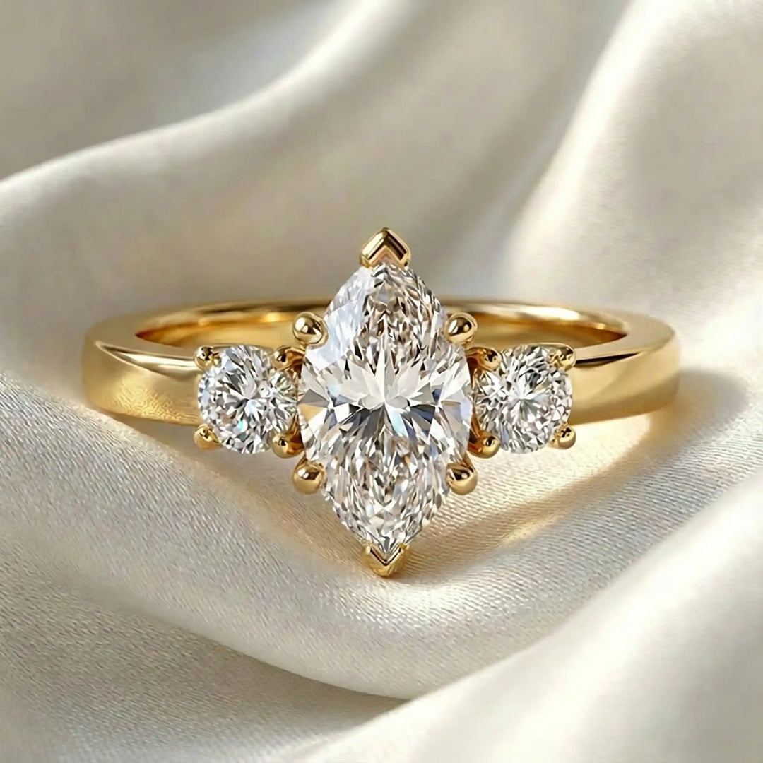 Marquise three-stone lab-grown diamond engagement ring displayed on soft fabric.
