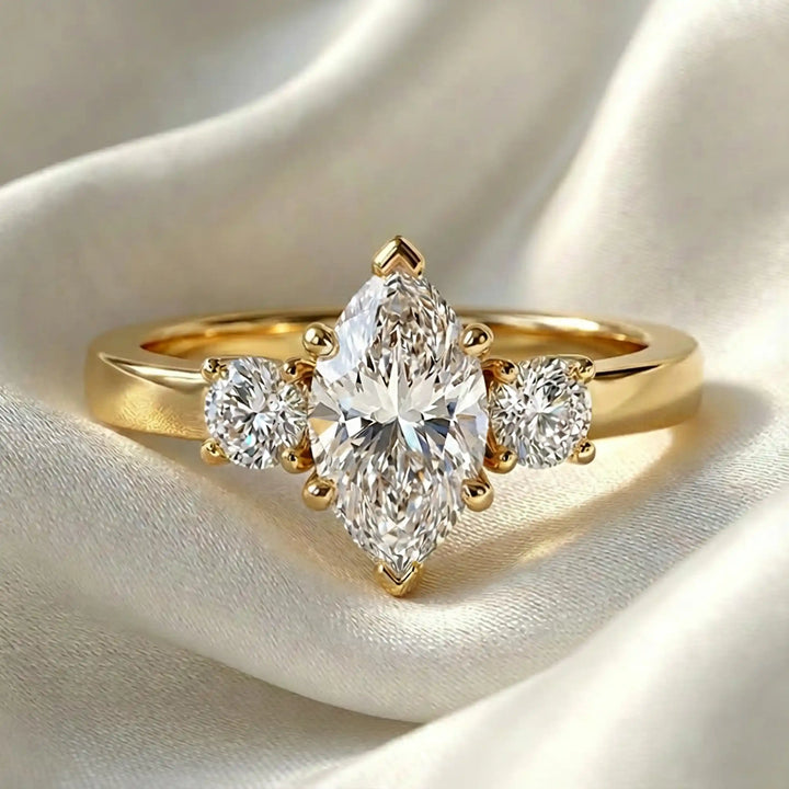 Marquise three-stone lab-grown diamond engagement ring displayed on soft fabric.
