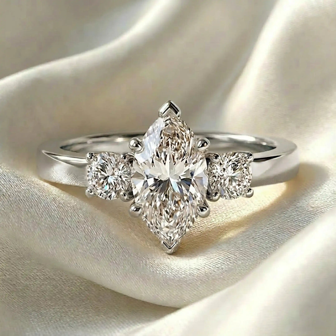 Marquise three-stone lab-grown diamond engagement ring displayed on soft fabric.
