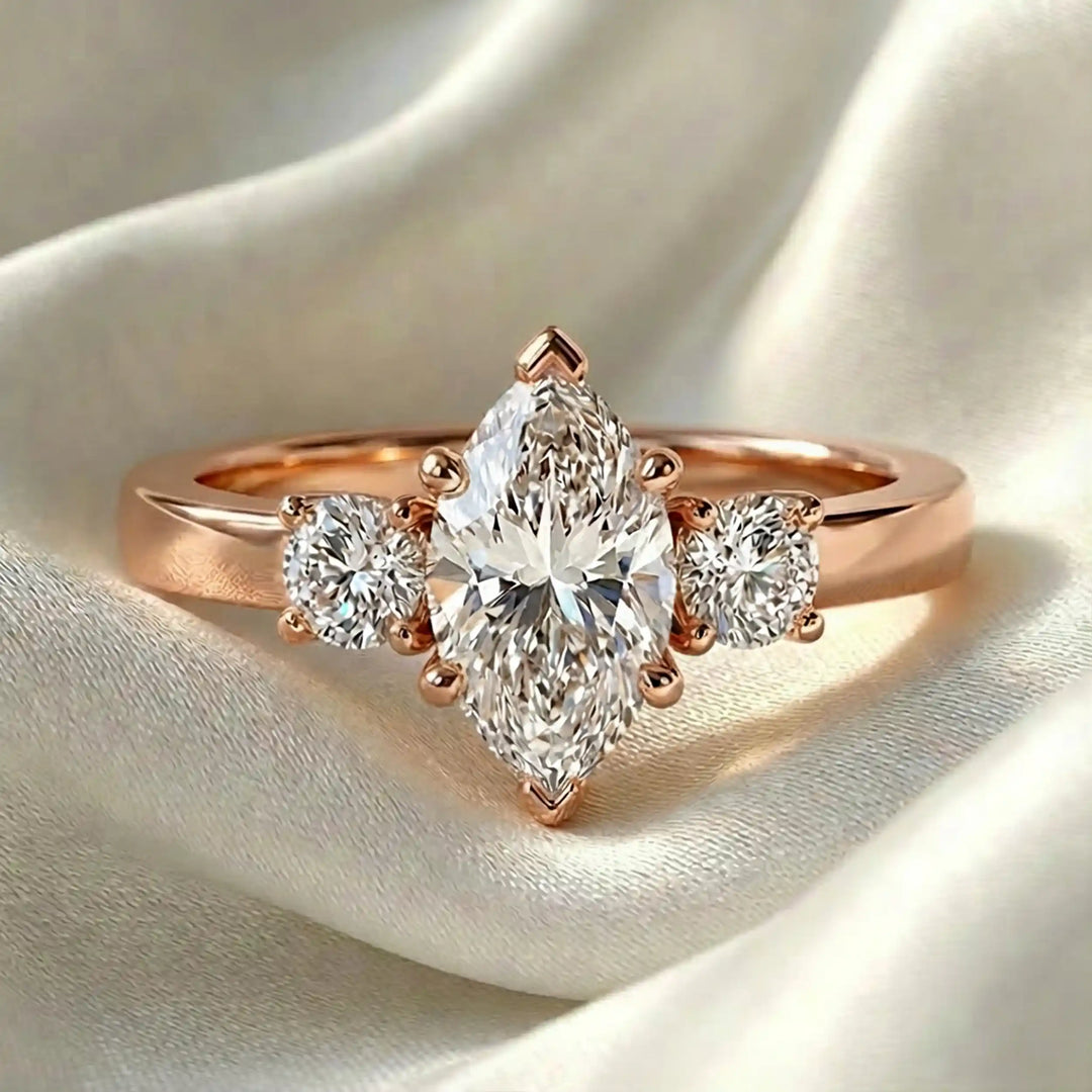 Marquise three-stone lab-grown diamond engagement ring displayed on soft fabric.
