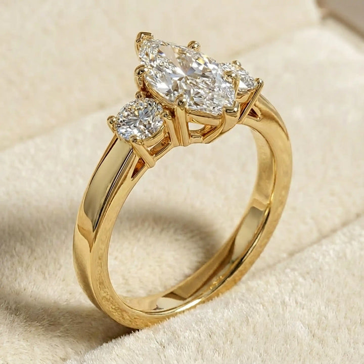 Marquise three-stone lab-grown diamond engagement ring displayed on soft fabric.
