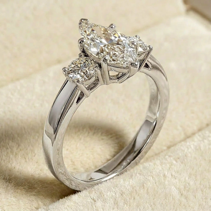 Marquise three-stone lab-grown diamond engagement ring displayed on soft fabric.
