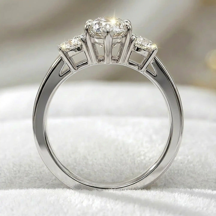 Marquise three-stone lab-grown diamond engagement ring displayed on soft fabric.
