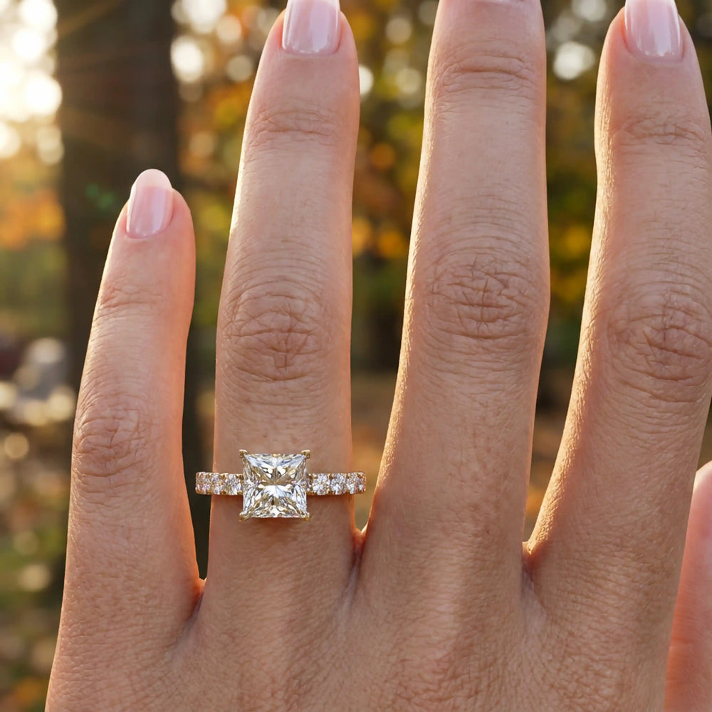Princess cut lab diamond engagement ring with diamond band shown on hand.