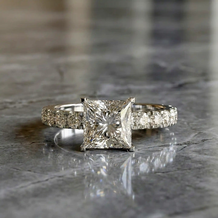 Princess cut lab diamond engagement ring with diamond band shown on marble display.