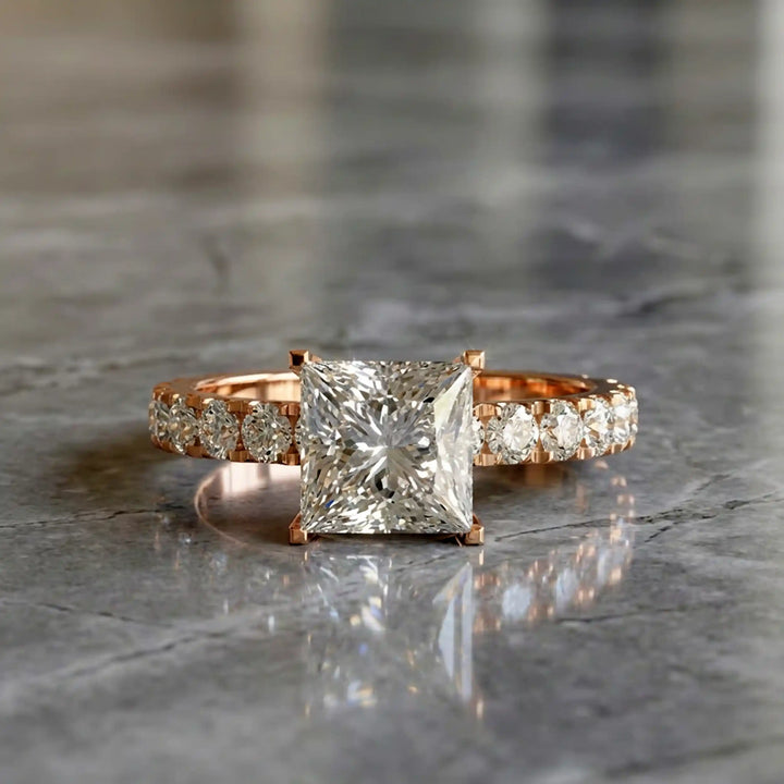 Princess cut lab diamond engagement ring with diamond band shown on marble display.