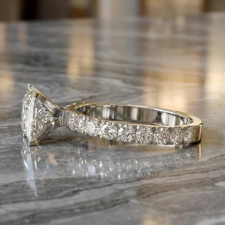 Princess cut lab diamond engagement ring with diamond band shown on marble display.