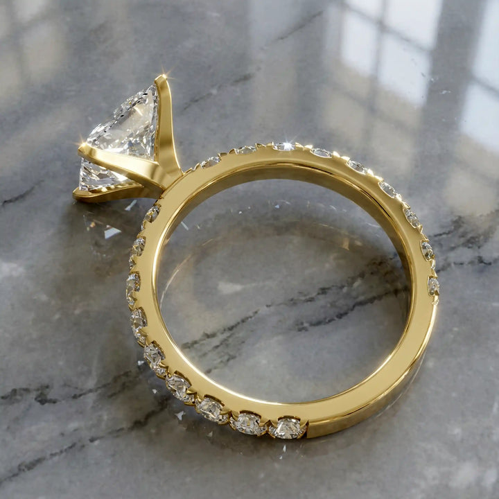 Princess cut lab diamond engagement ring with diamond band shown on marble display.