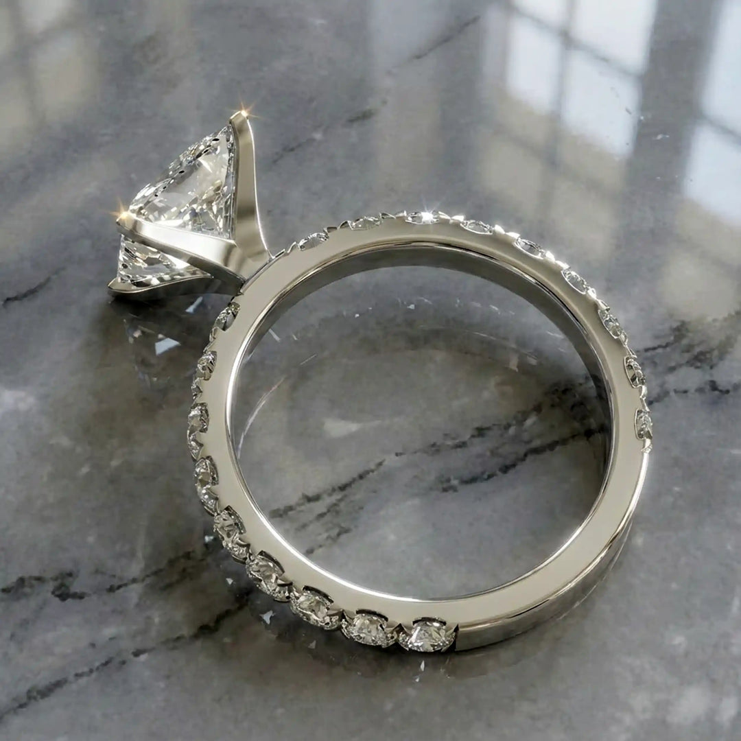 Princess cut lab diamond engagement ring with diamond band shown on marble display.