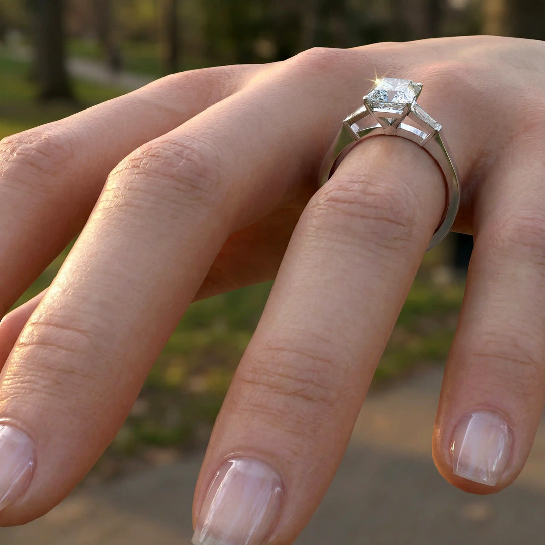 Radiant cut lab diamond three-stone engagement ring on hand.