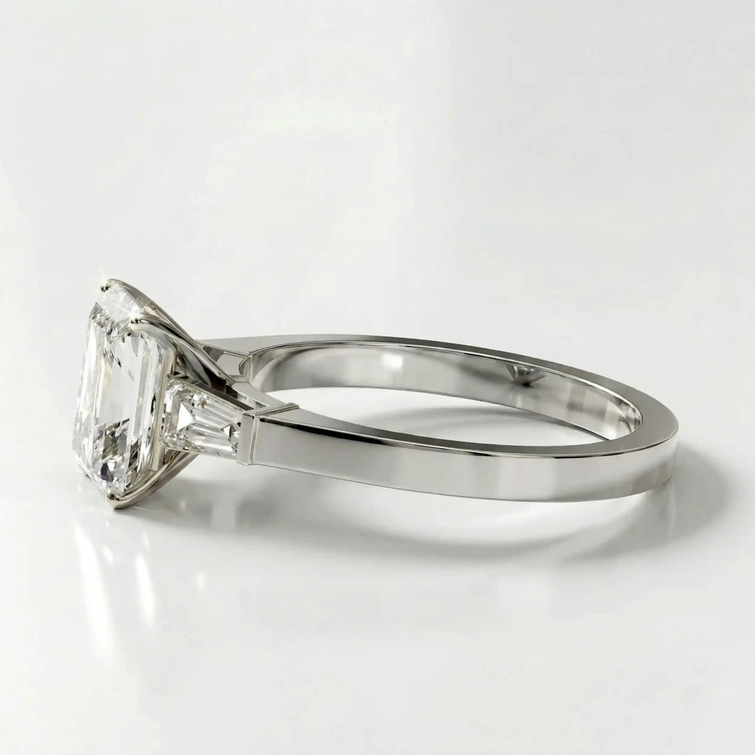 Radiant cut lab diamond three-stone engagement ring shown white surface.