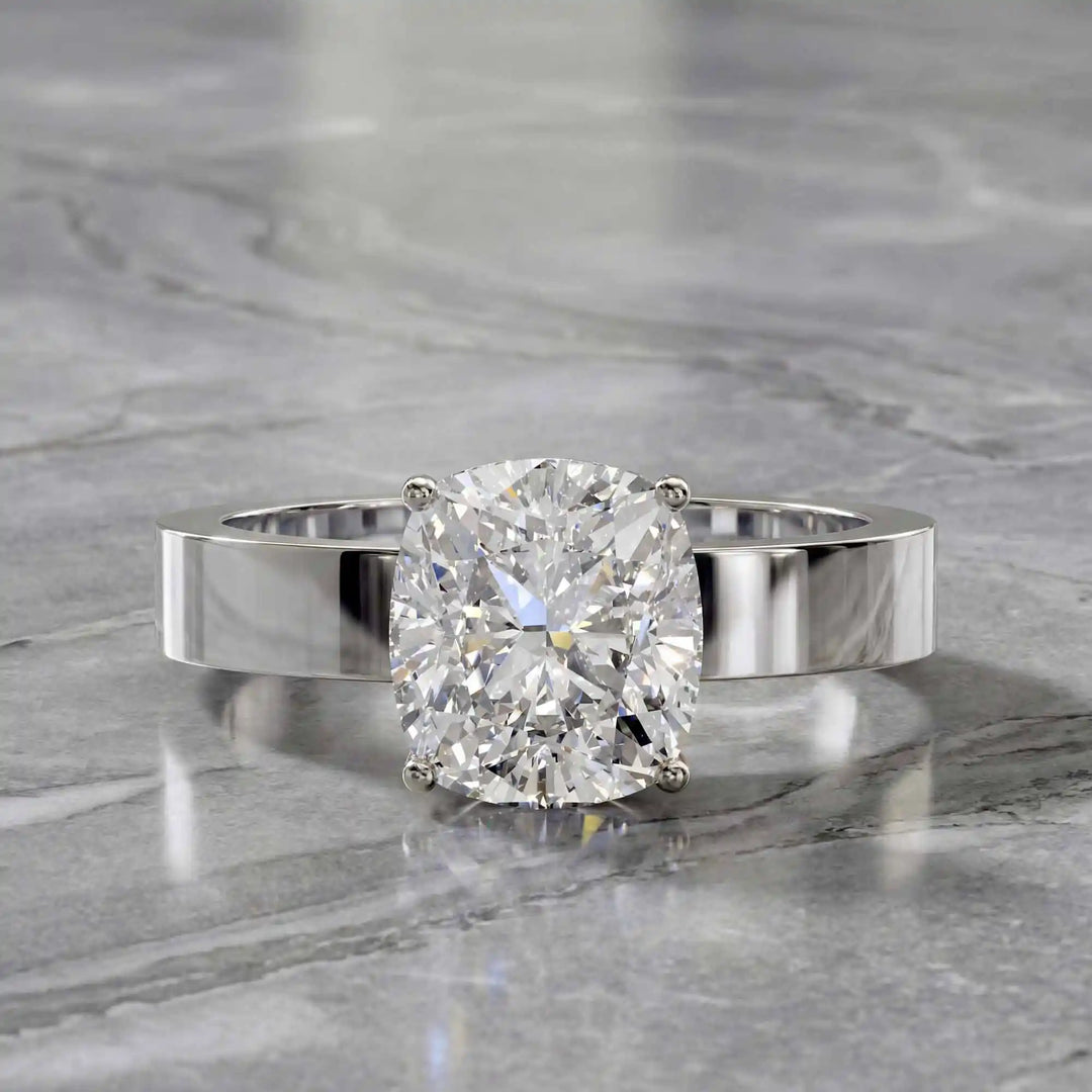 Elongated cushion lab grown diamond solitaire ring on wide flat band shown on display.