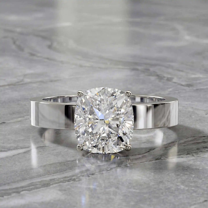 Elongated cushion lab grown diamond solitaire ring on wide flat band shown on display.