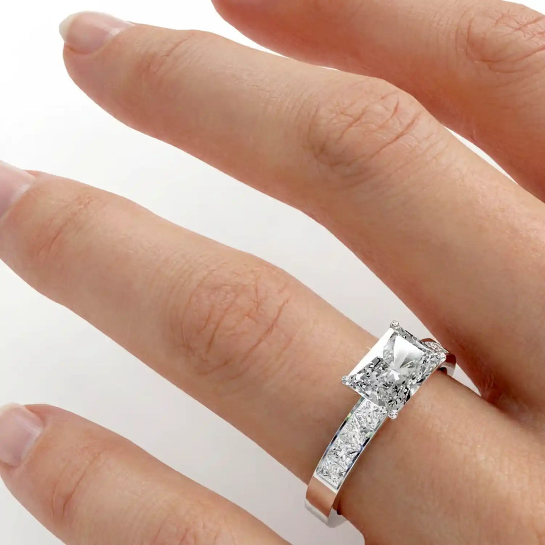 Radiant lab-grown diamond east-west engagement ring with channel-set princess side stones displayed on hand.