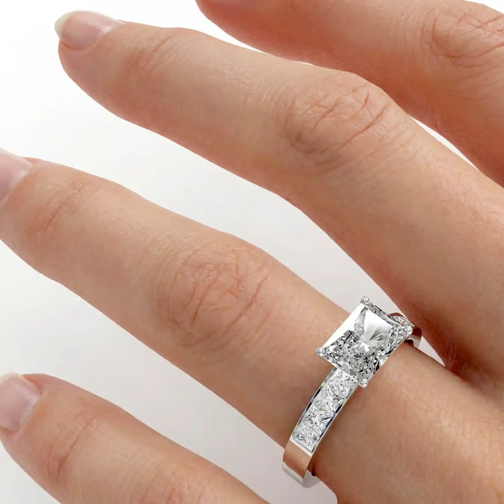 Radiant lab-grown diamond east-west engagement ring with channel-set princess side stones displayed on hand.