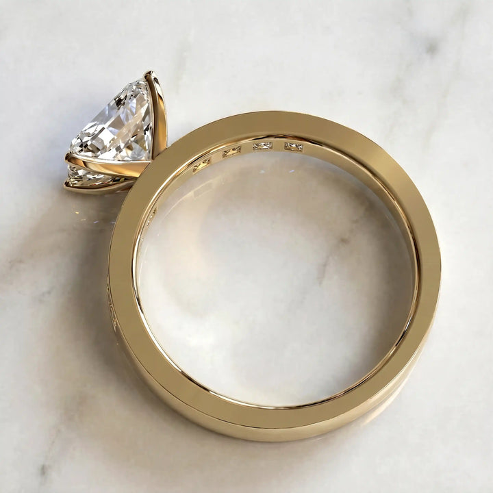 Radiant lab-grown diamond east-west engagement ring with channel-set princess side stones displayed on surface.