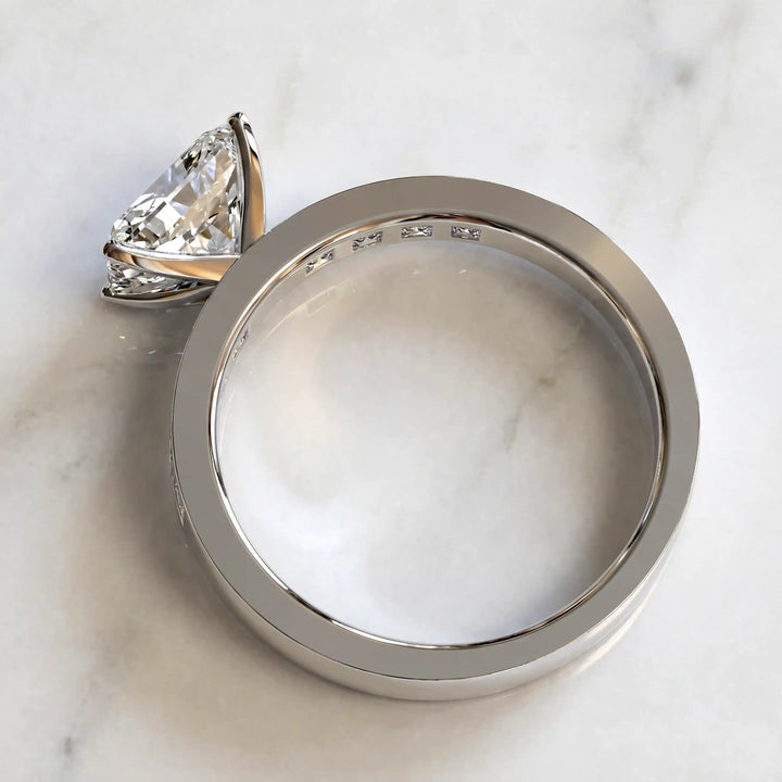 Radiant lab-grown diamond east-west engagement ring with channel-set princess side stones displayed on surface.
