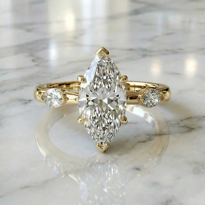 2.5 carat three stone marquise lab-grown diamond engagement ring displayed on marble surface.
