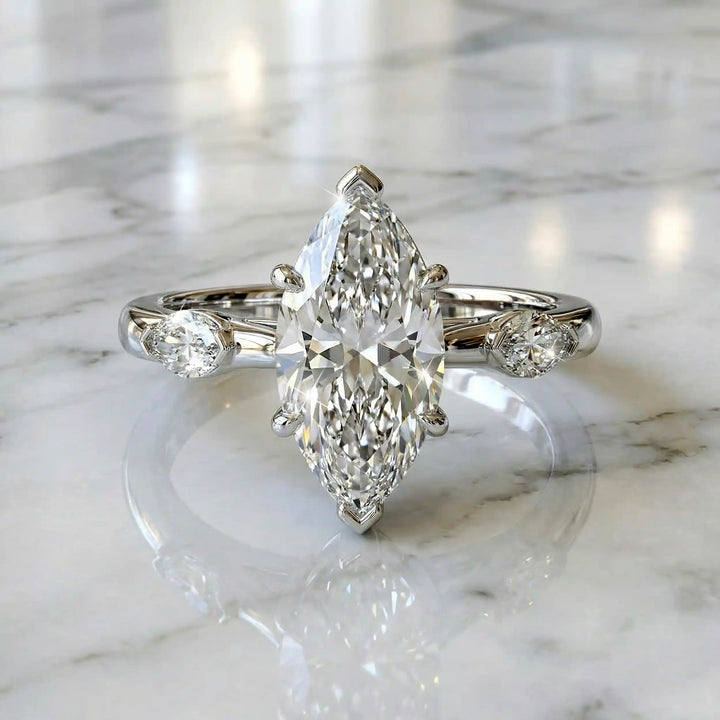 2.5 carat three stone marquise lab-grown diamond engagement ring displayed on marble surface.
