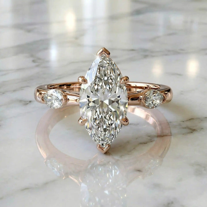 2.5 carat three stone marquise lab-grown diamond engagement ring displayed on marble surface.
