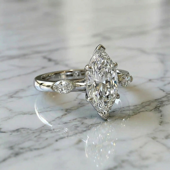 2.5 carat three stone marquise lab-grown diamond engagement ring displayed on marble surface.
