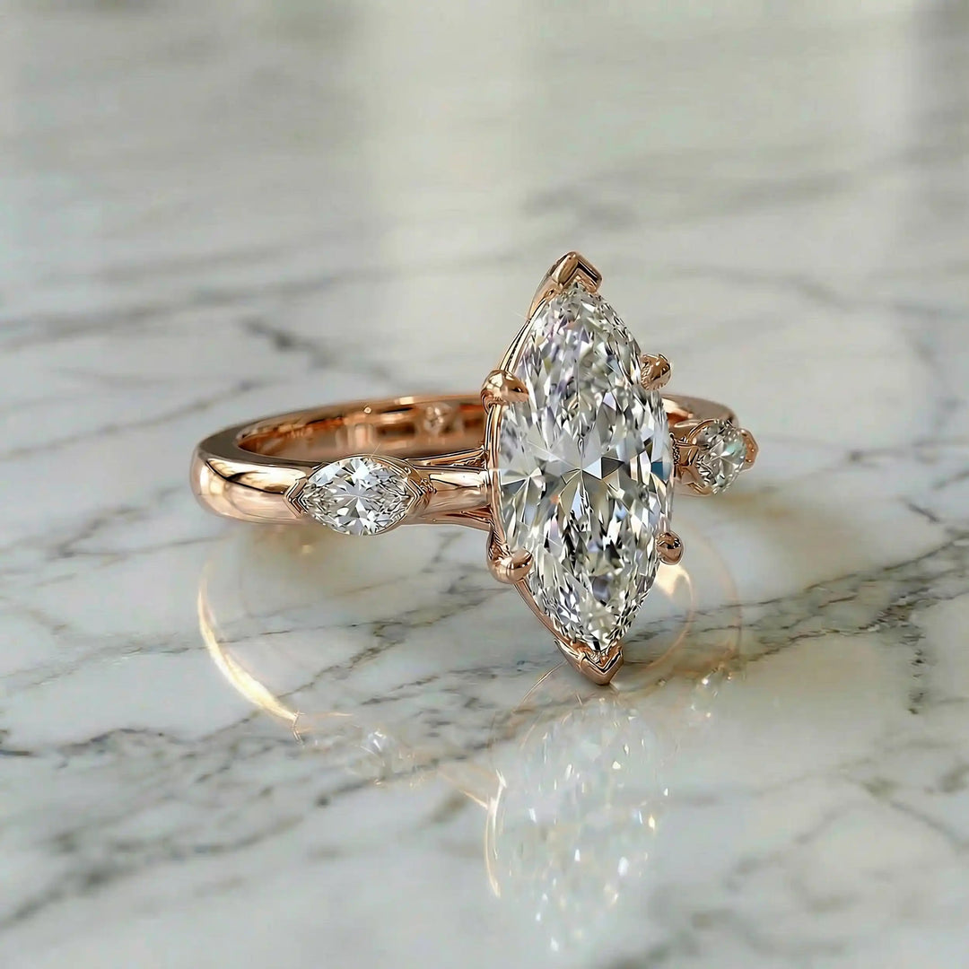 2.5 carat three stone marquise lab-grown diamond engagement ring displayed on marble surface.
