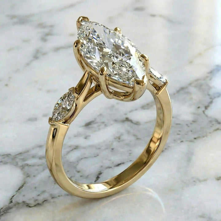 2.5 carat three stone marquise lab-grown diamond engagement ring displayed on marble surface.
