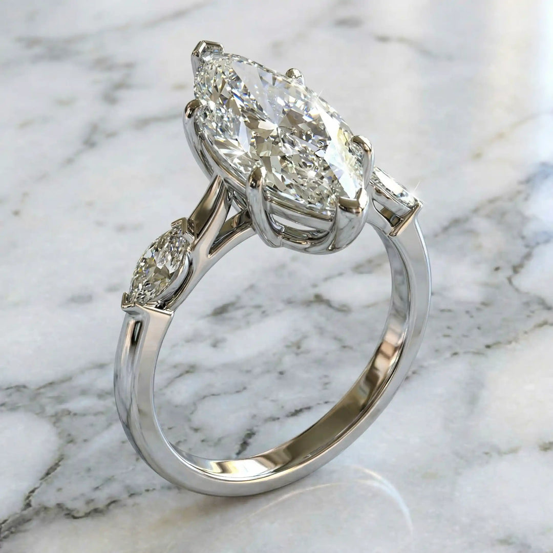 2.5 carat three stone marquise lab-grown diamond engagement ring displayed on marble surface.
