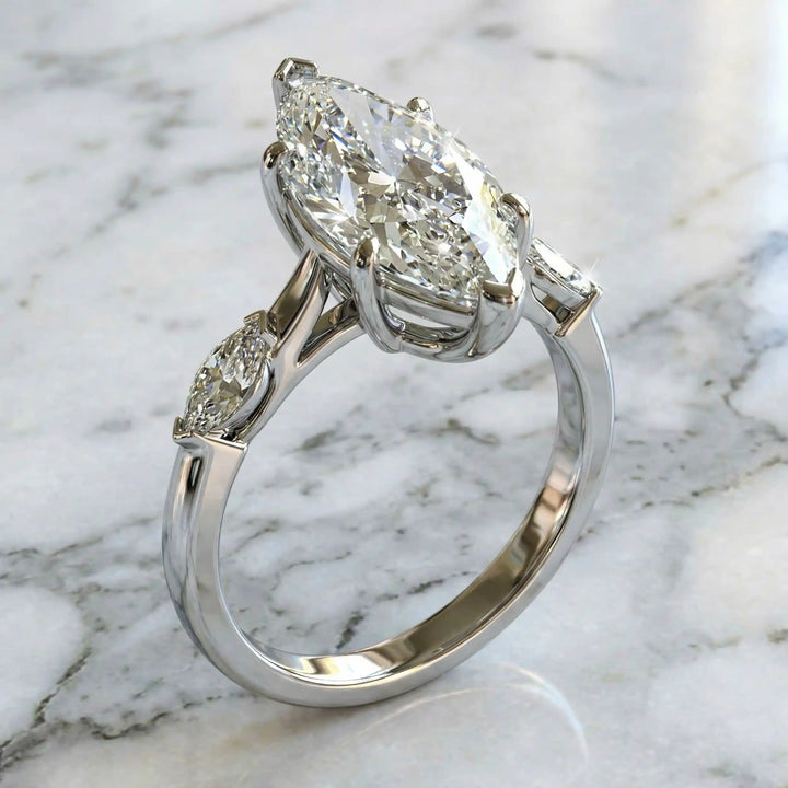 2.5 carat three stone marquise lab-grown diamond engagement ring displayed on marble surface.
