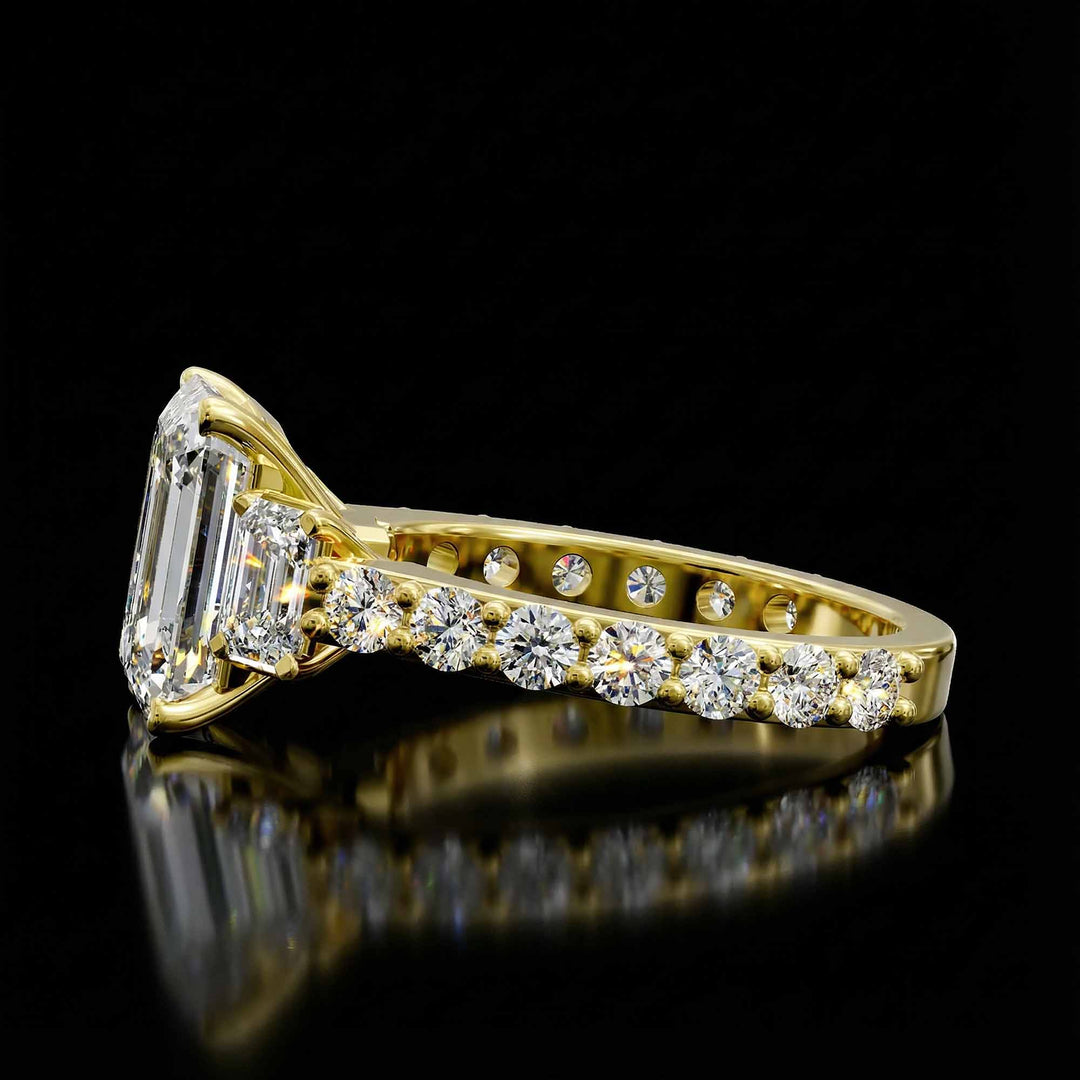 Emerald cut three stone diamond engagement ring with pavé band on display.
