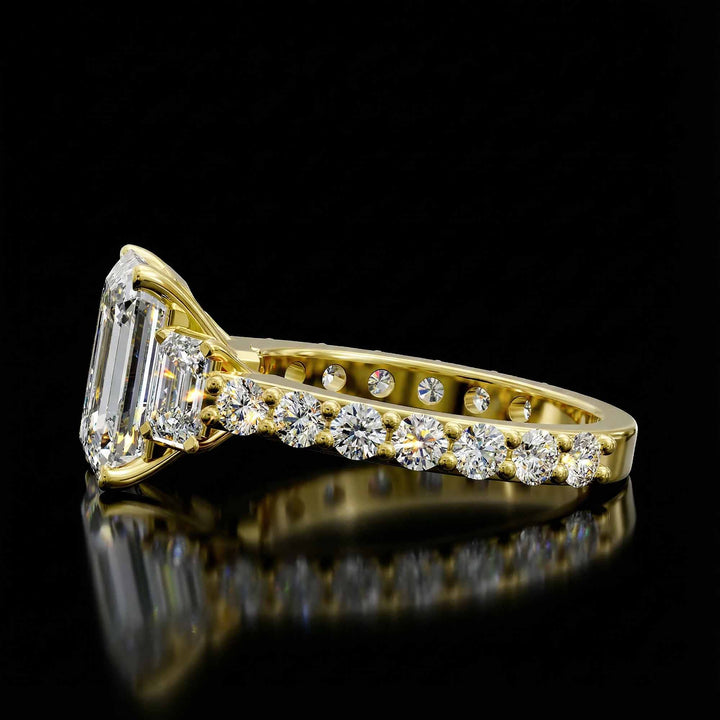 Emerald cut three stone diamond engagement ring with pavé band on display.
