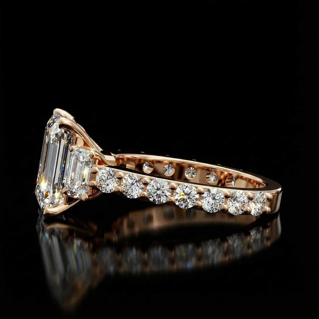 Emerald cut three stone diamond engagement ring with pavé band on display.
