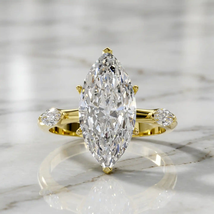 Marquise lab-grown diamond three-stone engagement ring with hidden halo shown on marble display.
