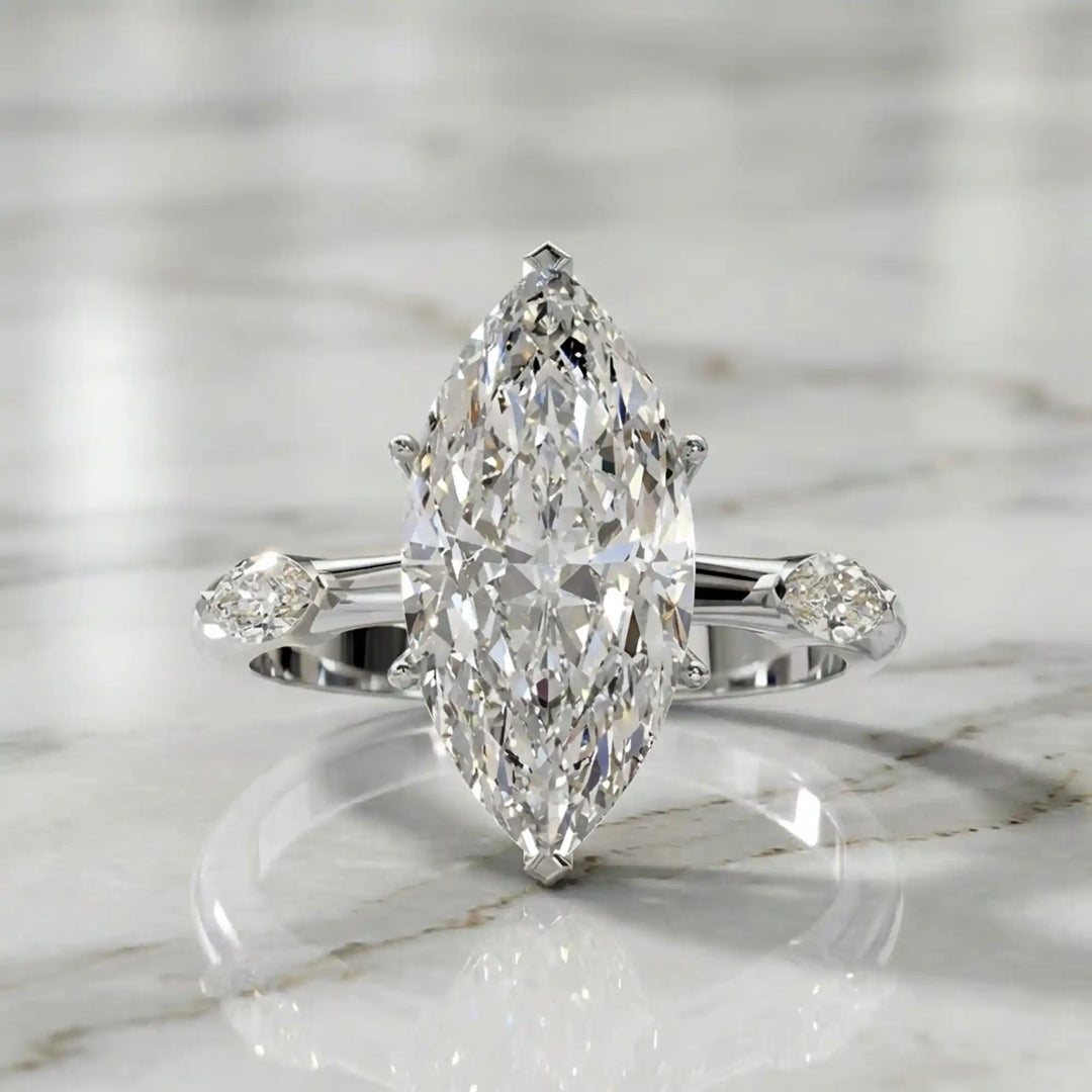 Marquise lab-grown diamond three-stone engagement ring with hidden halo shown on marble display.