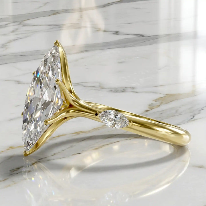 Marquise lab-grown diamond three-stone engagement ring with hidden halo shown on marble display.