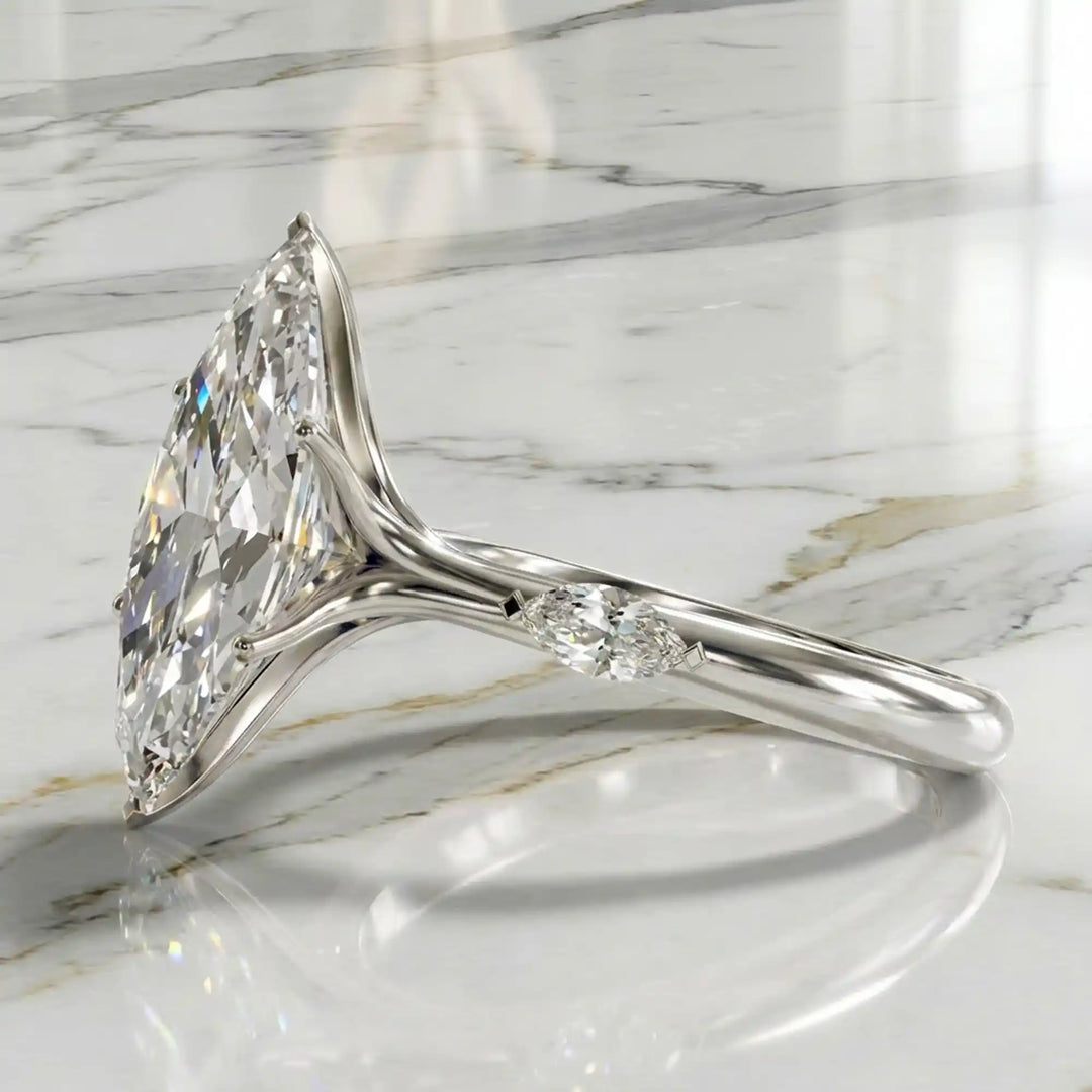 Marquise lab-grown diamond three-stone engagement ring with hidden halo shown on marble display.